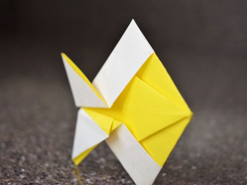 yellow and white origami fish on gray background