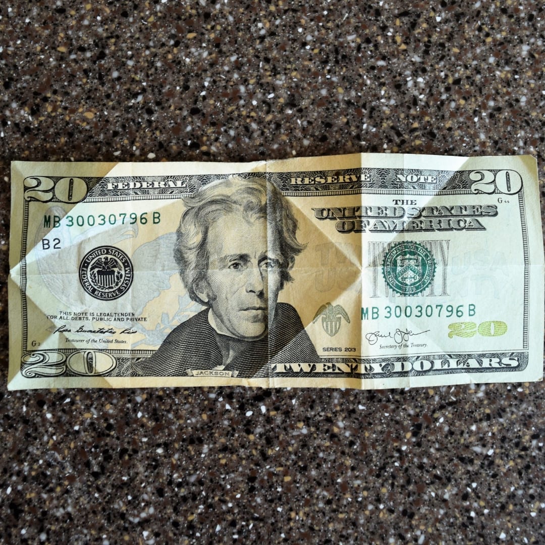 Us curreny twenty dollar bill with folded crease pattern on dark gray background